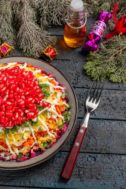 Side close-up view dish spruce branches plate of appetizing dish and fork oil and spruce branches with Christmas tree toys