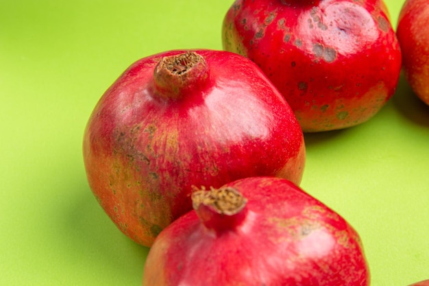 Side close-up view fruits apples pomegranates on the green surface