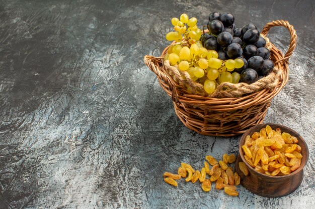 Side close-up view fruits the basket of the appetizing grapes next to the bowl of dried fruits