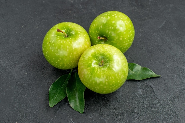 Free photo side close-up view green apples the appetizing green apples with leaves on the dark table