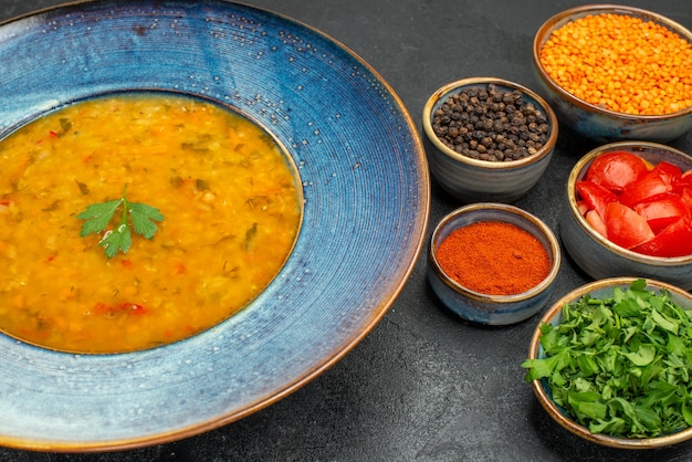 Free photo side close-up view lentil soup lentil soup spices tomatoes lentil herbs in the bowls