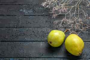 Free photo side close-up view pears on table green pears next to tree branches on the right side of wooden grey table