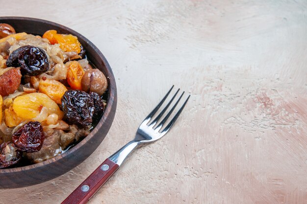 Side close-up view pilaf rice chestnuts dried fruits in the bowl fork