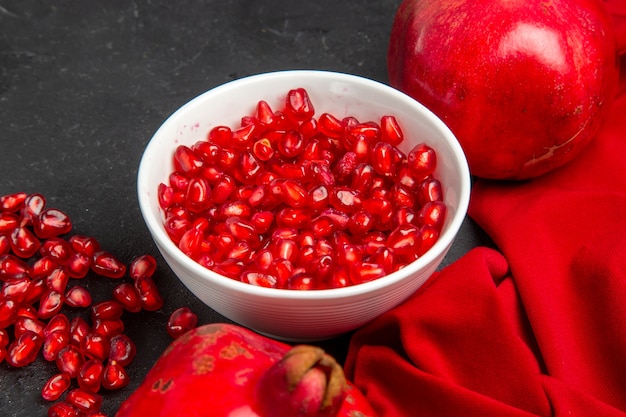 Side close-up view pomegranate red tablecloth pomegranates bowl of pomegranate seeds