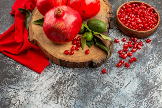 Free photo side close-up view pomegranates a bowl of seeds of pomegranate pomegranates with green leaves