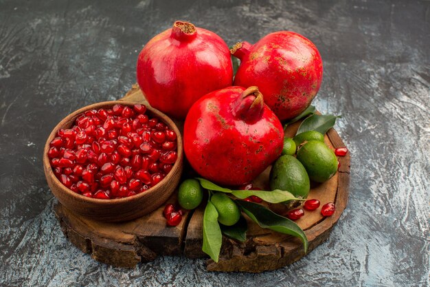 Side close-up view pomegranates ripe pomegranate and citrus fruits with leaves on the board