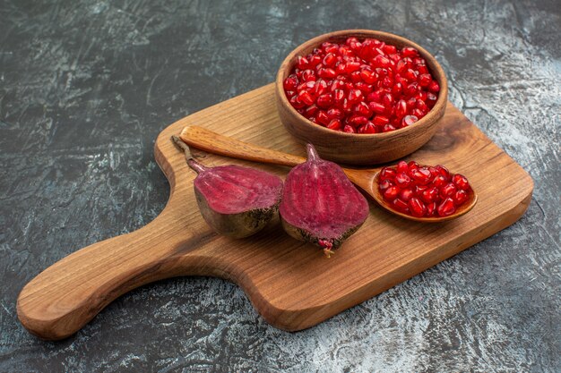 Side close-up view vegetables the cutting board with the appetizing pomegranate seeds spoon beets