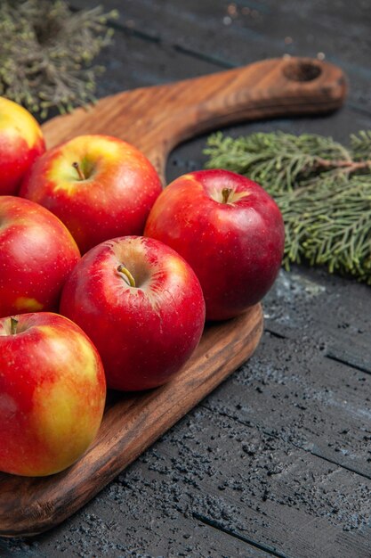 Side close view apples and branches yellow-red apples on a cutting board on wooden grey background between tree branches