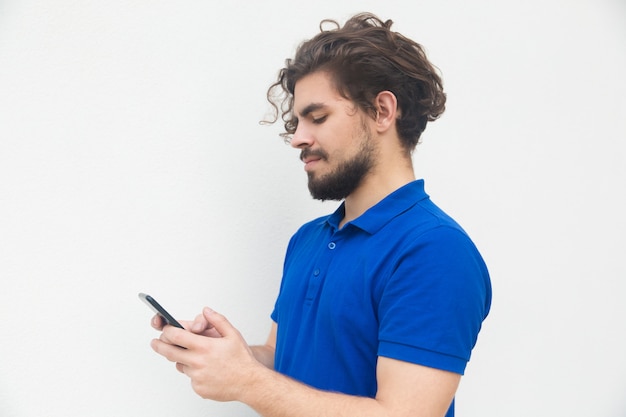 Side of focused guy texting message on smartphone