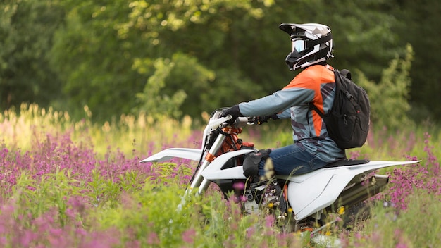 Side view active man riding motorbike in the forrest