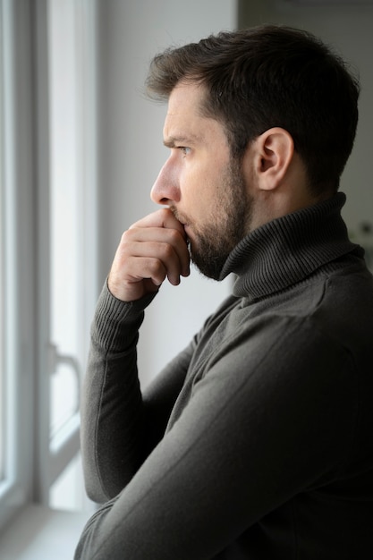 Free Photo side view anxious man looking out the window