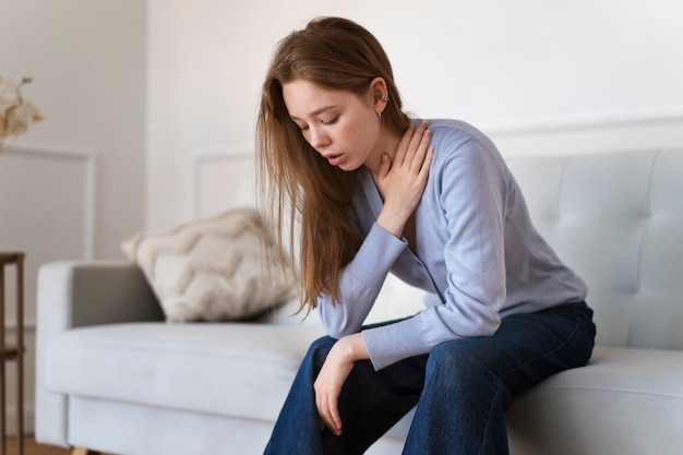 Side view anxious woman sitting on couch at home