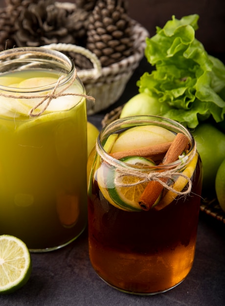 Side view apple drinks fresh apple juice and lemon tea with lime cinnamon green apple and lettuce on black board