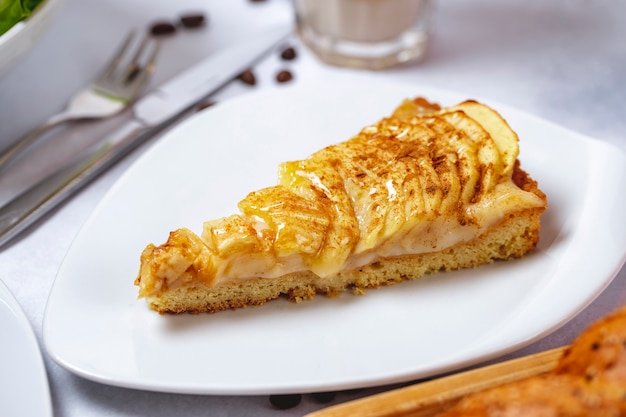 Side view apple pie with cream and cinnamon on a plate