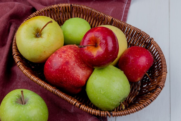 side view of apples in basket on bordo cloth and wooden