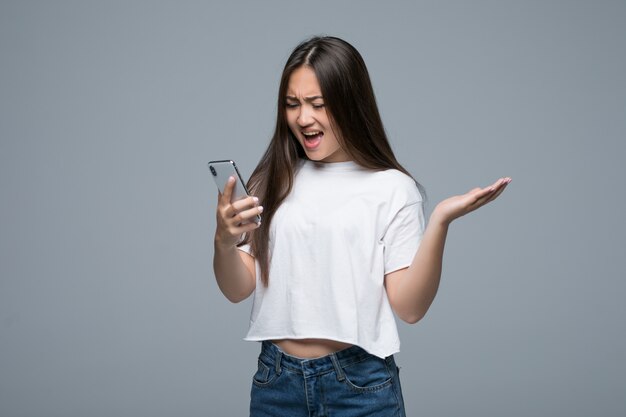 Side view of asian woman holding smartphone and looking back over gray background