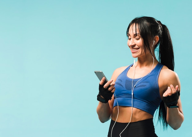 Side view of athletic woman in gym outfit enjoying music