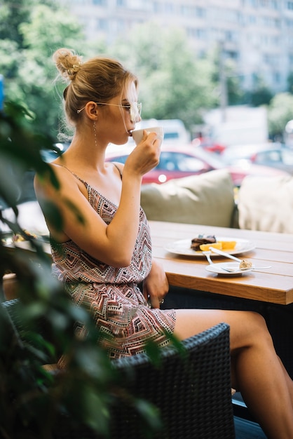 Side view of attractive young woman drinking coffee at caf���