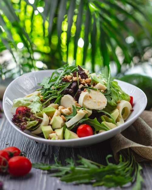 Side view avocado salad with lettuce greens tomato cheese and peanut