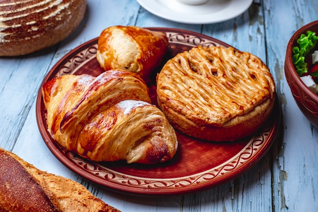 Side view baked goods croissant with sugar powder and puff pastry on a plate