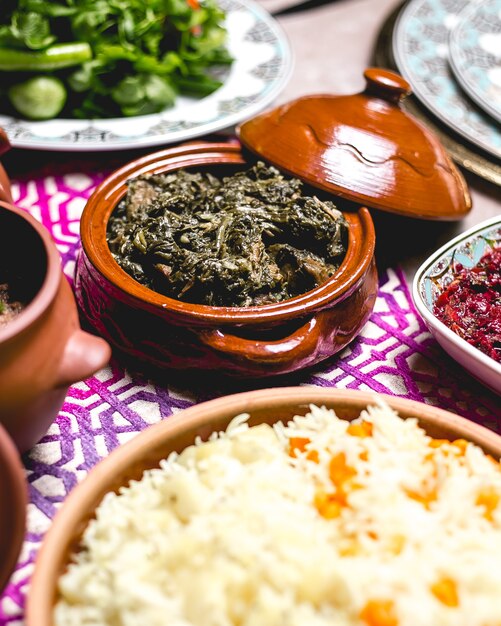 Side view baked meat with greens in a pot with boiled rice