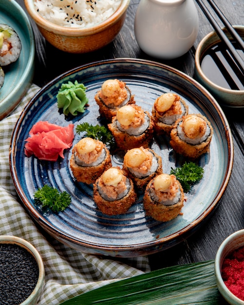 Free Photo side view of baked sushi rolls with shrimps ginger and wasabi on a plate served with soy sauce on wood