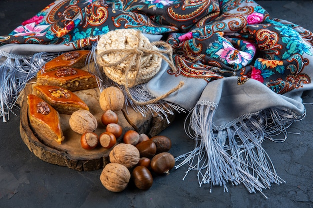 Free photo side view of baklava with whole nuts and rice breads on shawl with tassel