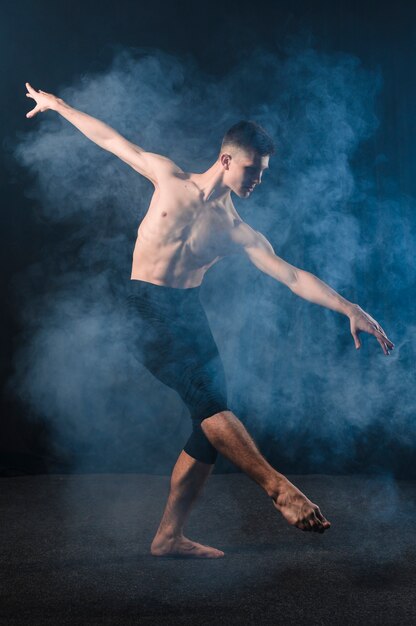 Free photo side view of ballerino dancing in tights with smoke