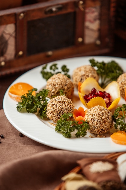 Free photo side view balls in sesame seeds with decor herbs carrots and mandarin slices