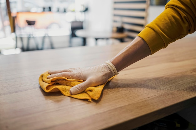 Side view of barista cleaning table while wearing latex glove