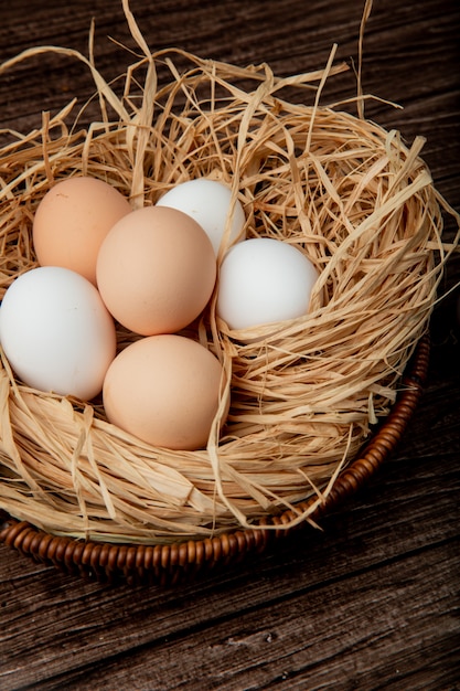 Side view of basket of eggs in nest on wooden background