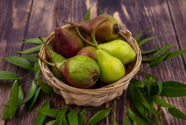 Side view of basket of peaches with leaves on wooden surface