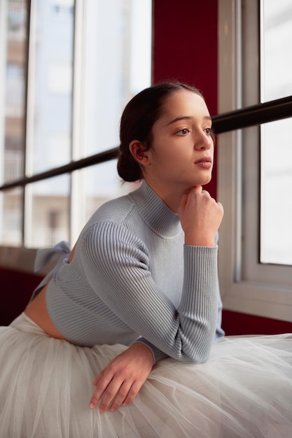 Side view of beautiful ballerina in tutu skirt looking through the window