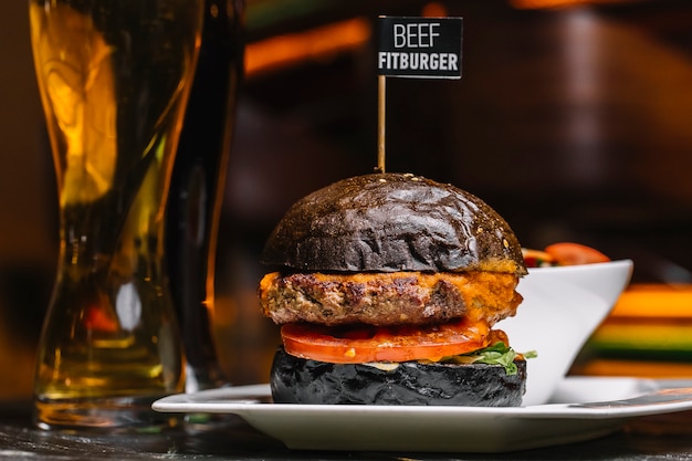 Free Photo side view beef fitburger on a black bun with a glass of beer