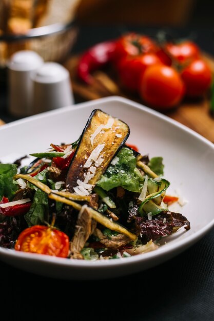 Side view of beef salad with grilled eggplant avocado peppers cherry tomatoes garlic and pormesan cheese in a bowl