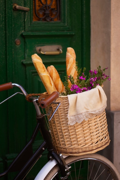 Free photo side view bicycle basket with baguette and flowers