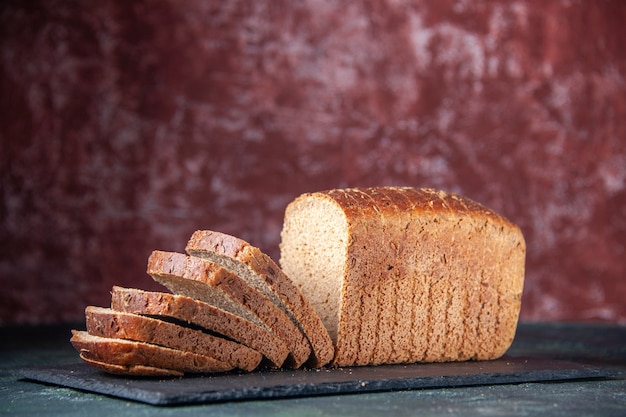 Free Photo side view of black bread slices on black board on mixed colors distressed background