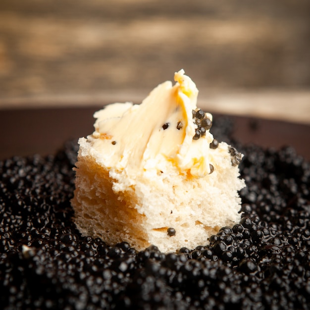 Free photo side view black caviar with bread and butter on dark background.