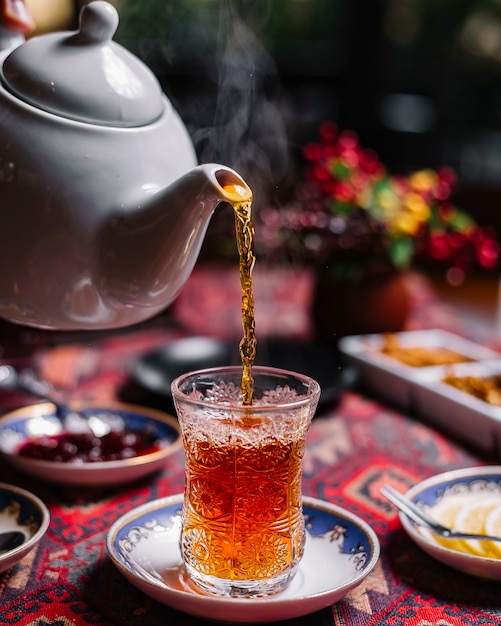 Side view black tea in pear-shape glass on the table