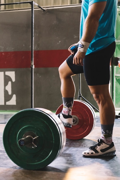 Side view bodybuilding concept with man putting foot on barbell