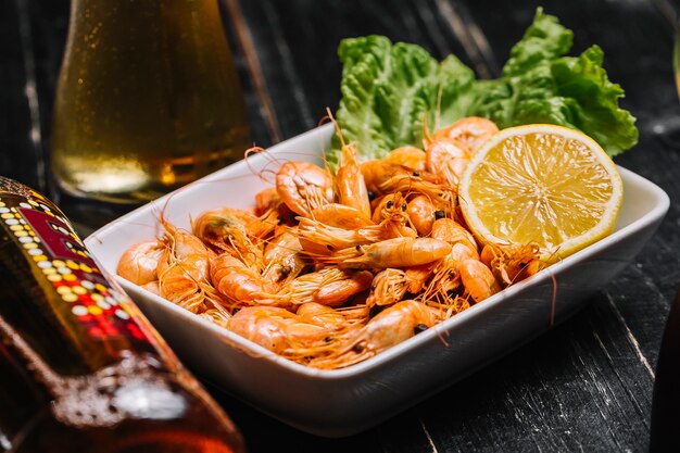 Side view boiled river shrimps on a leaf of lettuce with lemon