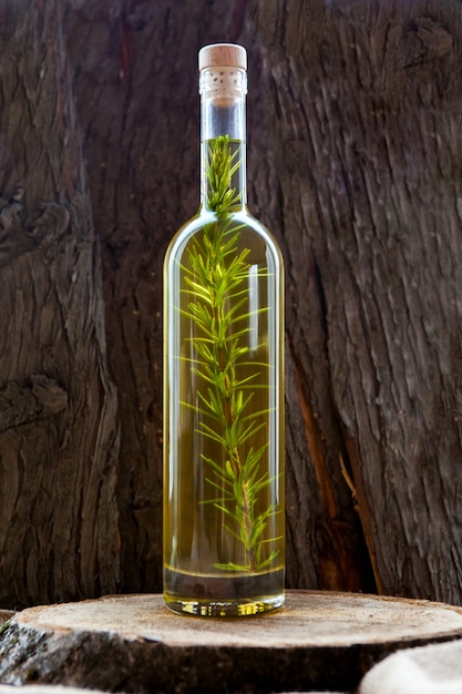 Free photo side view bottle with olive oil on wooden table