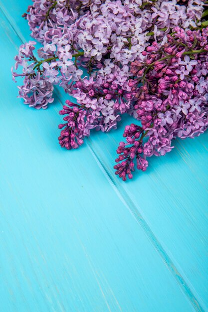 Side view of a bouquet of lilac flowers isolated on blue wooden background with copy space