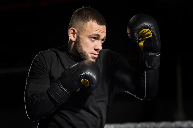 Free photo side view of boxer posing in protective gloves