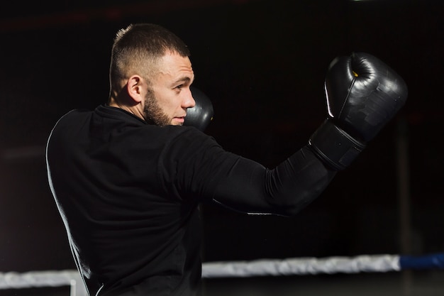 Free photo side view of boxer posing in protective gloves