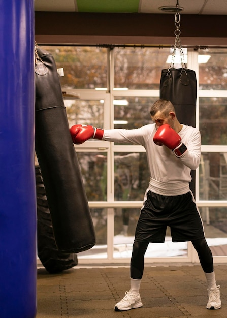 Free photo side view of boxer practicing with punching bag next to ring