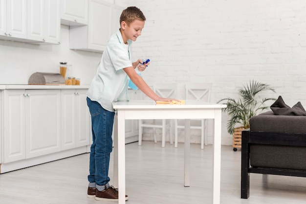 Free photo side view of boy cleaning the table