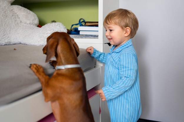 Free Photo side view  boy playing with dog indoors