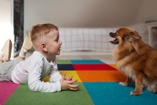 Free Photo side view  boy playing with dog indoors