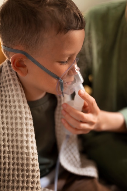 Free photo side view boy using a nebulizer